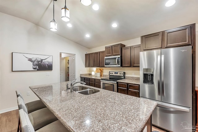 5853 Fairlands Rd, Milton, FL 32583 - kitchen with appliances with stainless steel finishes, a sink, vaulted ceiling, dark brown cabinetry, and an island with sink