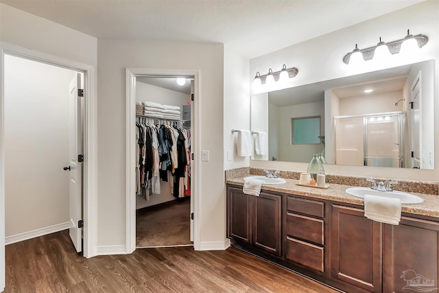 5853 Fairlands Rd, Milton, FL 32583 - bathroom featuring wood finished floors, a walk in closet, double vanity, baseboards, and a shower stall