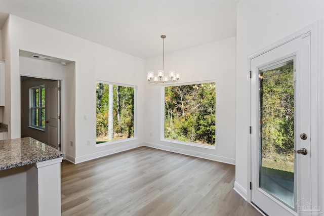 unfurnished dining area featuring an inviting chandelier and light hardwood / wood-style floors