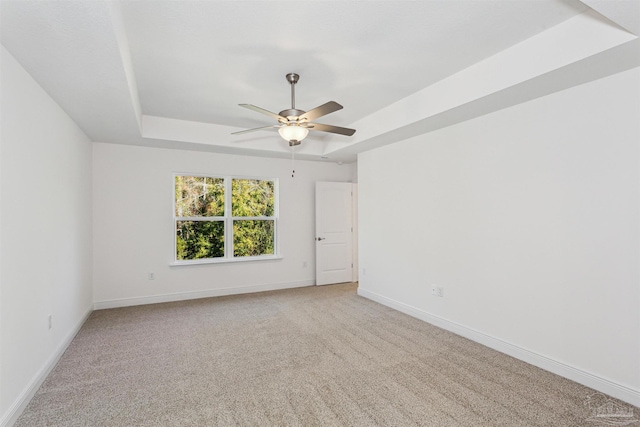 carpeted empty room with ceiling fan and a raised ceiling