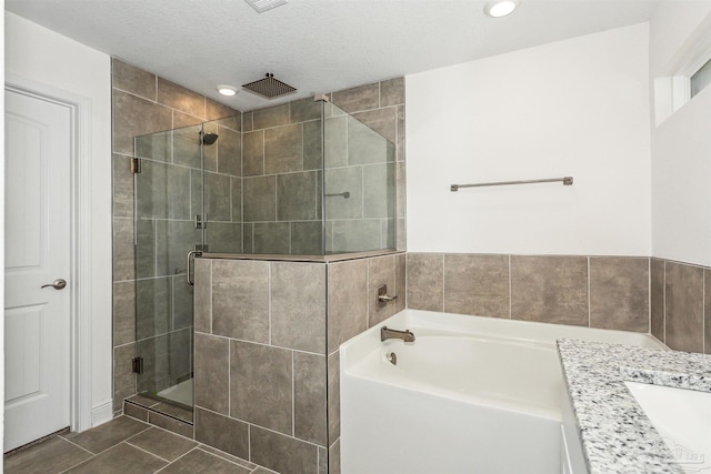 bathroom featuring shower with separate bathtub, a textured ceiling, tile patterned flooring, and vanity