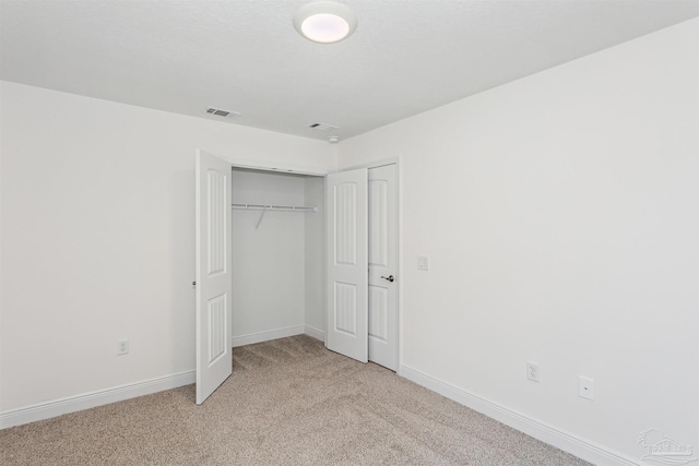 unfurnished bedroom featuring a closet and light colored carpet