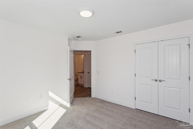 unfurnished bedroom with a closet and light colored carpet