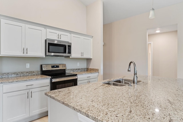 kitchen featuring white cabinetry, sink, hanging light fixtures, stainless steel appliances, and light stone counters