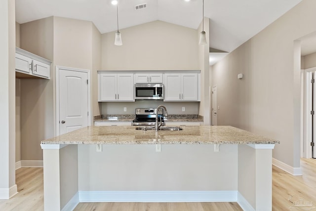 kitchen featuring light stone countertops, stainless steel appliances, sink, white cabinets, and hanging light fixtures