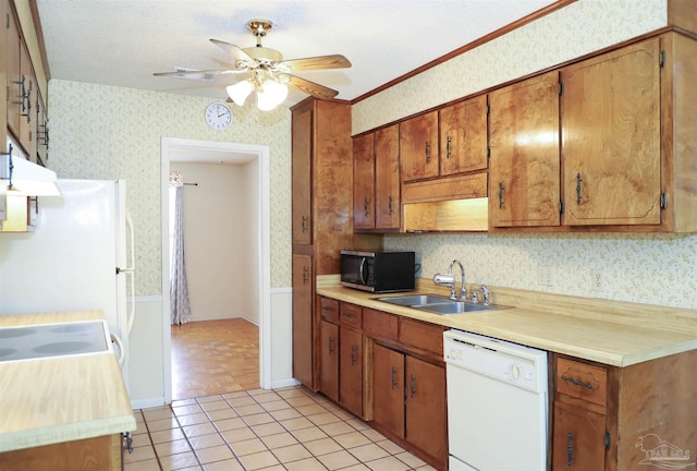 kitchen with wallpapered walls, white dishwasher, light countertops, and a sink