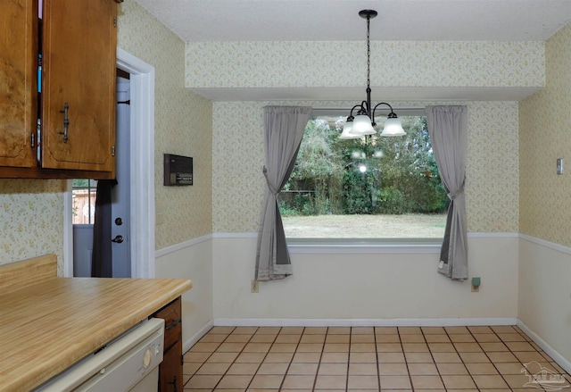 unfurnished dining area featuring light tile patterned floors, wainscoting, a textured ceiling, and wallpapered walls