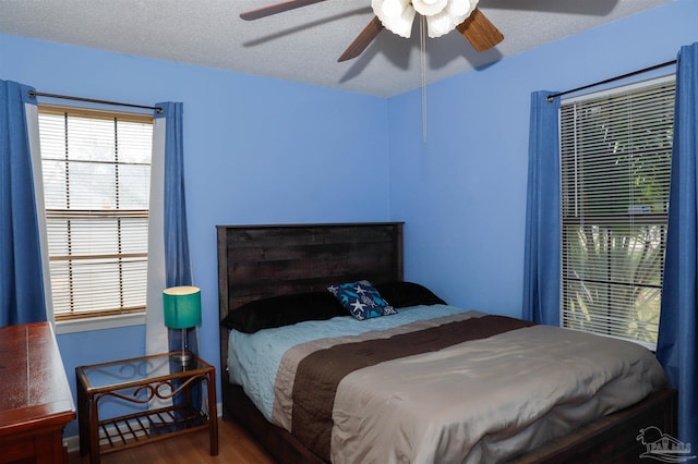 bedroom featuring a ceiling fan, a textured ceiling, and wood finished floors