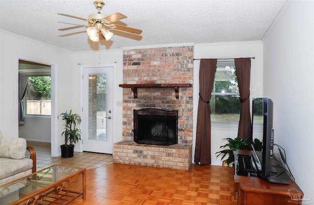 tiled living room with a brick fireplace, crown molding, a ceiling fan, and a textured ceiling