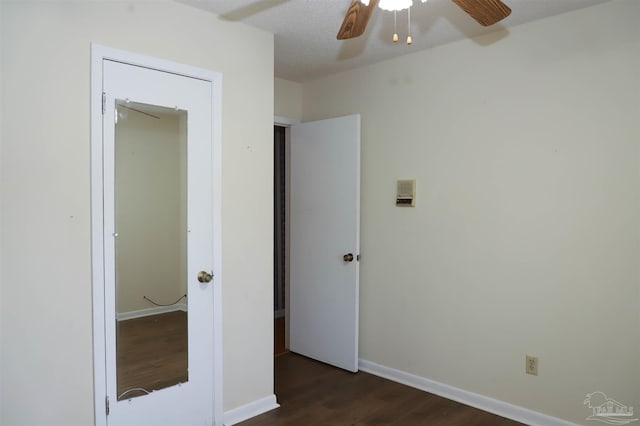 unfurnished bedroom with dark wood-style floors, a ceiling fan, and baseboards