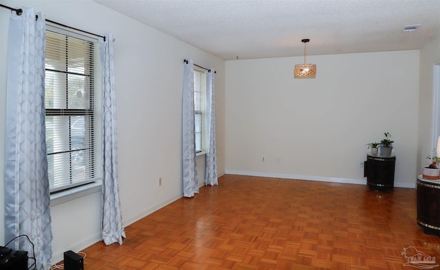 unfurnished room featuring a textured ceiling, visible vents, a wealth of natural light, and baseboards