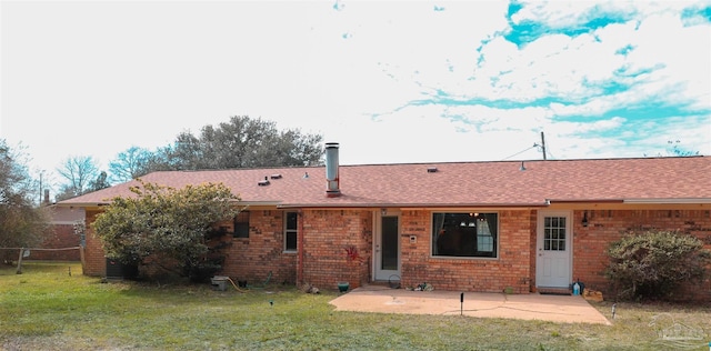 rear view of property featuring a patio, brick siding, a lawn, and roof with shingles