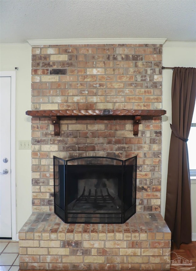 interior details featuring a brick fireplace, crown molding, and a textured ceiling