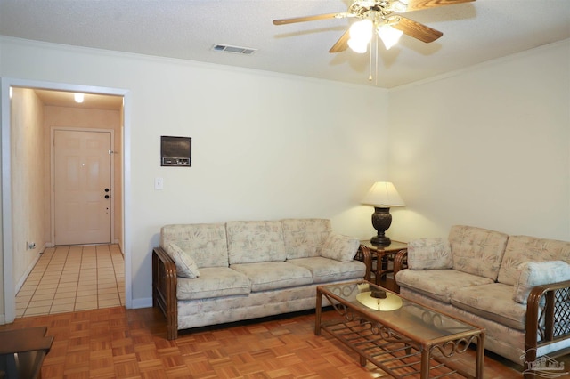 living room featuring a textured ceiling, visible vents, baseboards, a ceiling fan, and ornamental molding