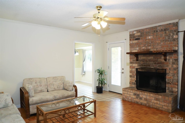 living room with ornamental molding, a brick fireplace, ceiling fan, a textured ceiling, and baseboards