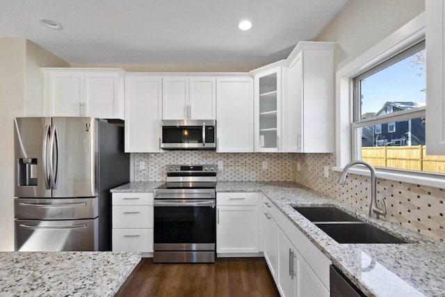 kitchen featuring sink, white cabinets, backsplash, stainless steel appliances, and light stone countertops