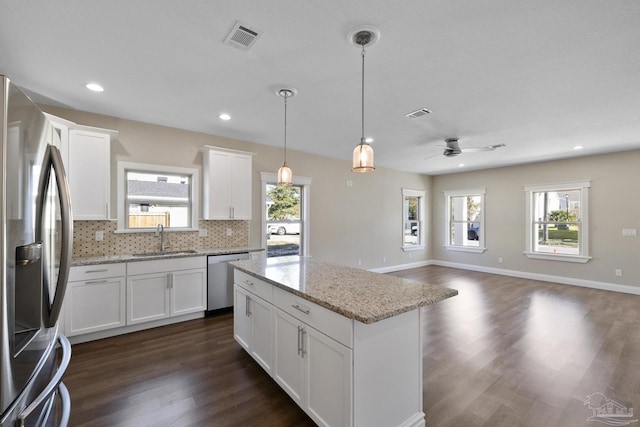 kitchen featuring decorative light fixtures, sink, white cabinets, stainless steel appliances, and light stone countertops