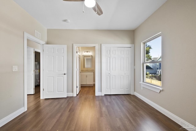 unfurnished bedroom with ensuite bathroom, ceiling fan, dark hardwood / wood-style flooring, and a closet