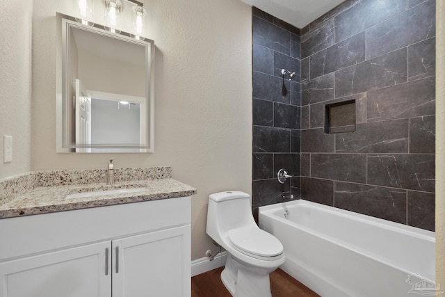 full bathroom featuring vanity, tiled shower / bath, hardwood / wood-style flooring, and toilet