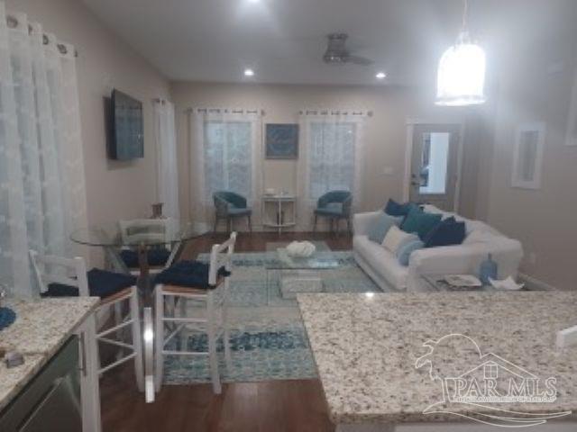 living room featuring dark wood-type flooring and ceiling fan