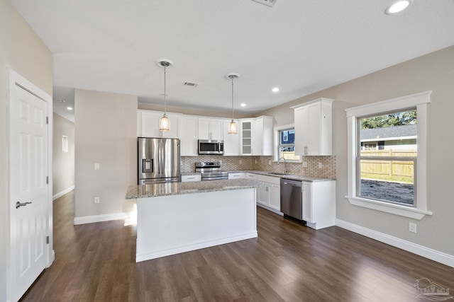 kitchen featuring white cabinetry, hanging light fixtures, stainless steel appliances, and a kitchen island