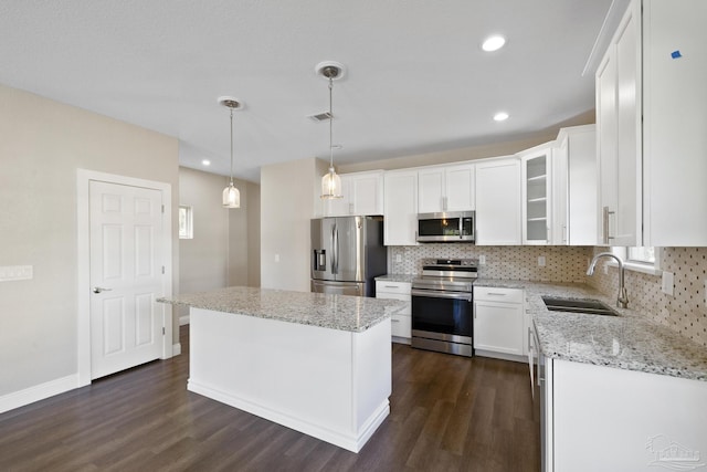 kitchen featuring appliances with stainless steel finishes, decorative light fixtures, white cabinetry, sink, and a center island