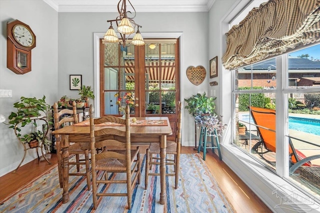 dining space with crown molding, baseboards, and wood finished floors