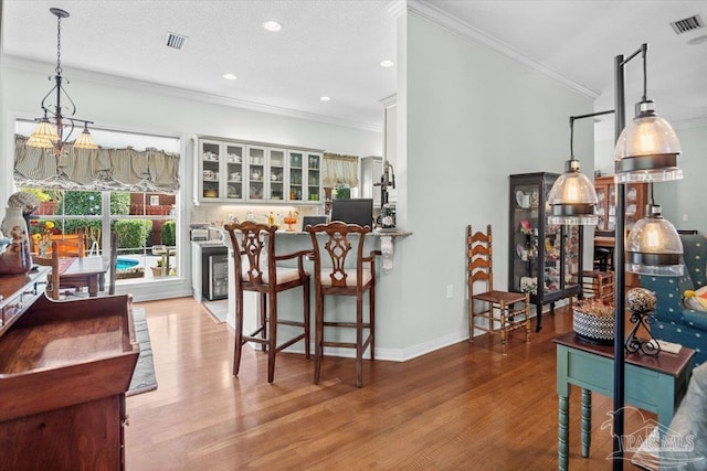 kitchen featuring crown molding, decorative light fixtures, a textured ceiling, and light wood-type flooring