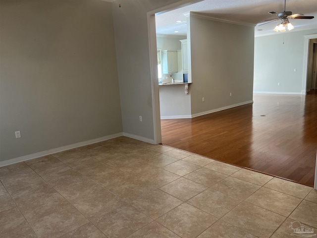empty room featuring crown molding, baseboards, ceiling fan, and tile patterned floors