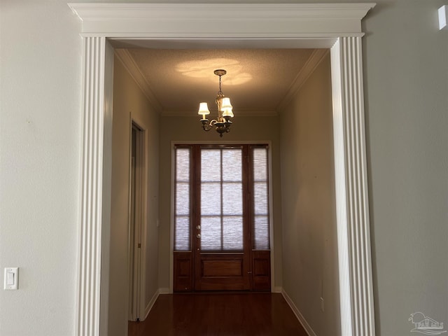doorway with baseboards, ornamental molding, a notable chandelier, and dark wood-style floors