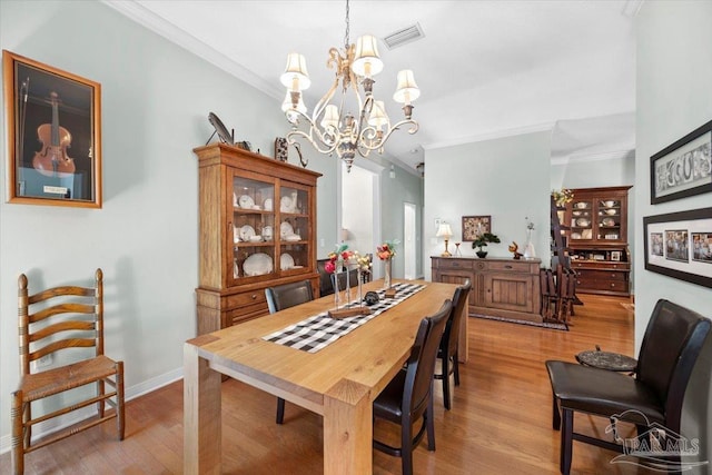 dining area featuring light hardwood / wood-style floors, crown molding, and a chandelier