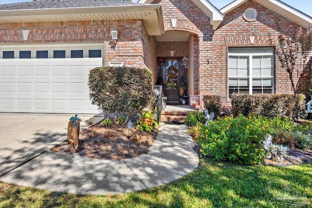 property entrance with brick siding, a garage, driveway, and a shingled roof