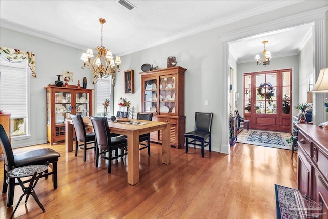 dining space with crown molding, a notable chandelier, hardwood / wood-style flooring, and plenty of natural light