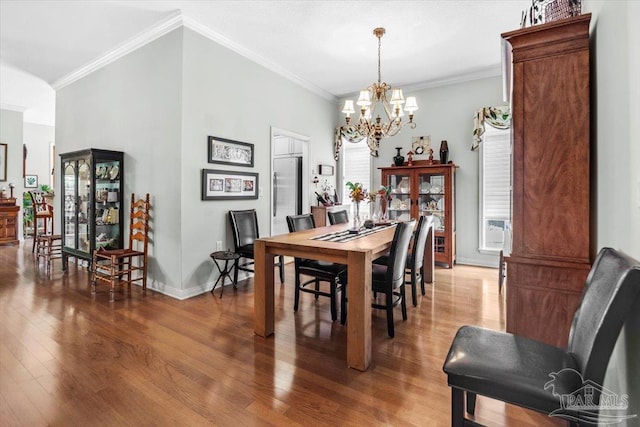 dining area with ornamental molding, a chandelier, and wood-type flooring