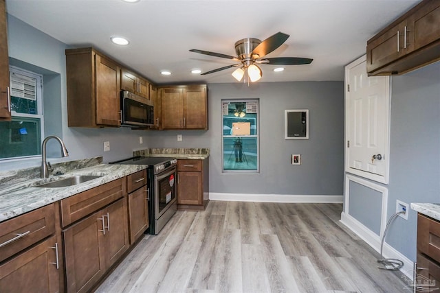 kitchen featuring sink, stainless steel electric range, ceiling fan, light stone counters, and light hardwood / wood-style floors