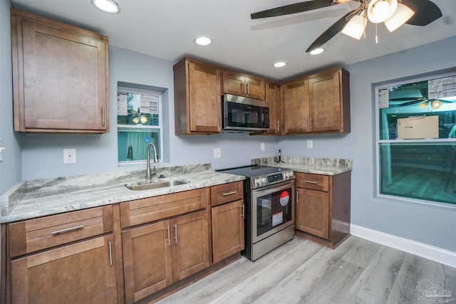 kitchen with sink, light hardwood / wood-style flooring, ceiling fan, stainless steel appliances, and light stone countertops