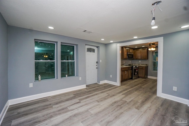 unfurnished living room with light hardwood / wood-style floors and a textured ceiling