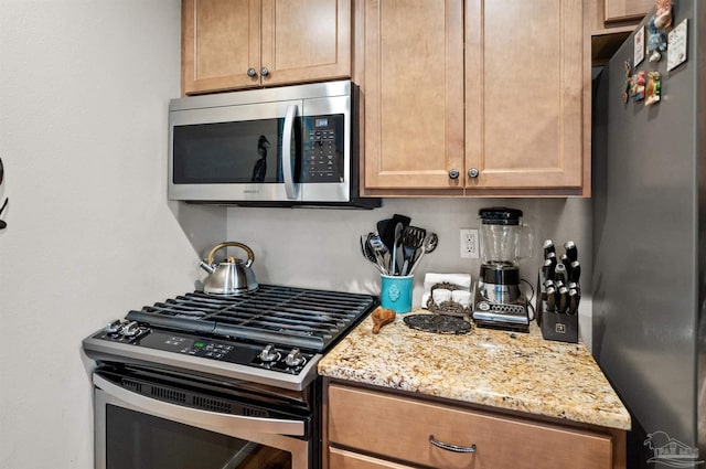 kitchen with appliances with stainless steel finishes and light stone counters