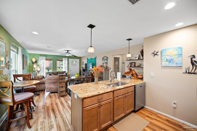 kitchen with pendant lighting, light hardwood / wood-style flooring, sink, and stainless steel dishwasher