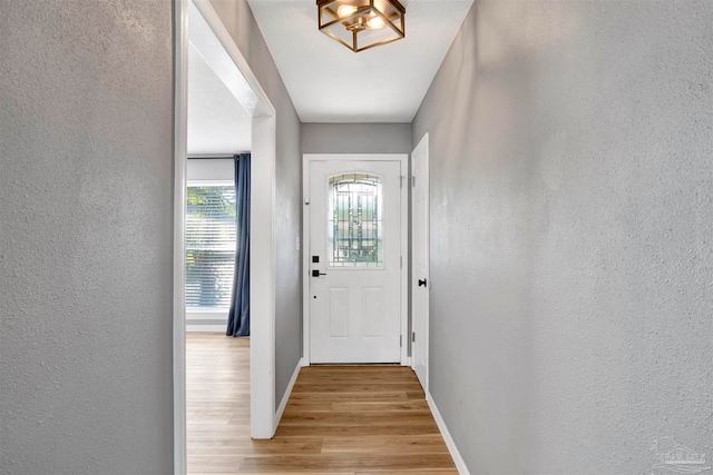 doorway featuring light wood-type flooring and a chandelier