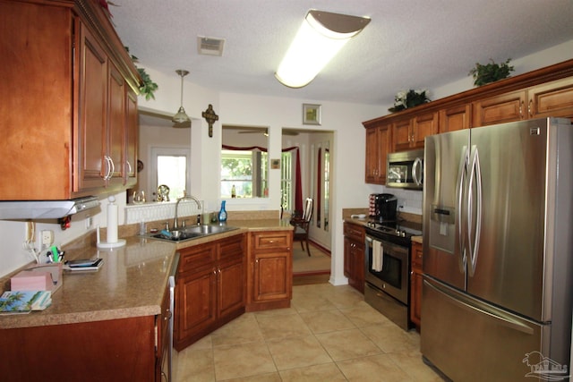 kitchen featuring appliances with stainless steel finishes, sink, light tile patterned flooring, a textured ceiling, and decorative light fixtures