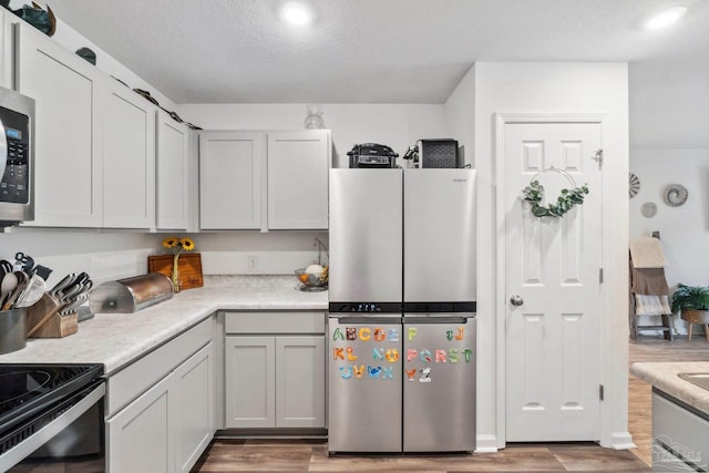 4348 Jitterbug St, Milton, FL 32583 - kitchen featuring appliances with stainless steel finishes, light wood-style flooring, light countertops, and a textured ceiling