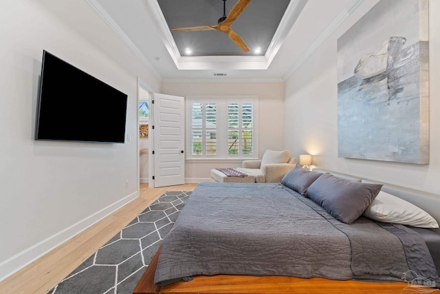 bedroom with ornamental molding, light hardwood / wood-style floors, ceiling fan, and a raised ceiling