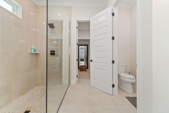 bathroom with toilet, a tile shower, and crown molding