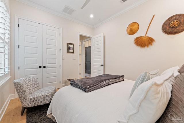 bedroom featuring ceiling fan, a closet, light wood-type flooring, and crown molding