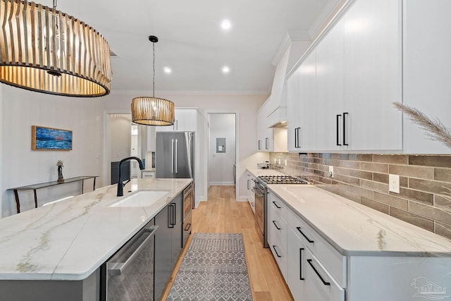 kitchen with white cabinetry, stainless steel appliances, a center island with sink, and sink