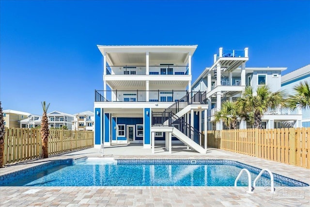 back of house featuring stairway, fence, a fenced in pool, and a patio