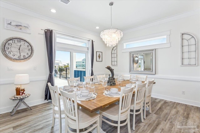 dining area featuring a chandelier, ornamental molding, wood finished floors, and baseboards