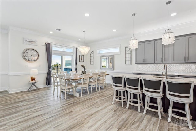 dining area featuring baseboards, visible vents, crown molding, and light wood finished floors