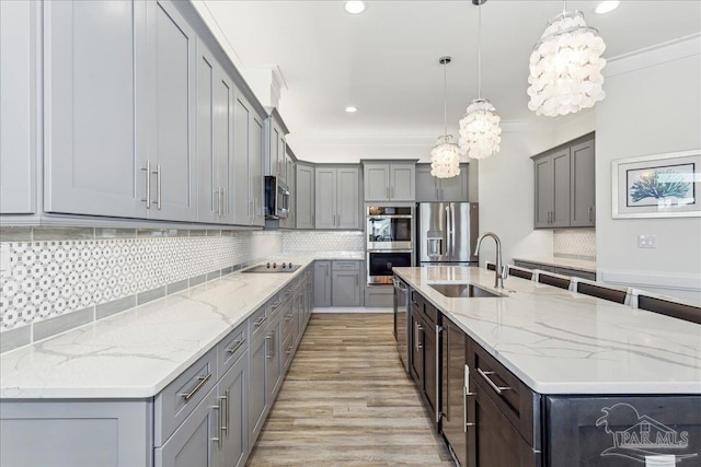 kitchen with a spacious island, gray cabinets, crown molding, stainless steel appliances, and a sink